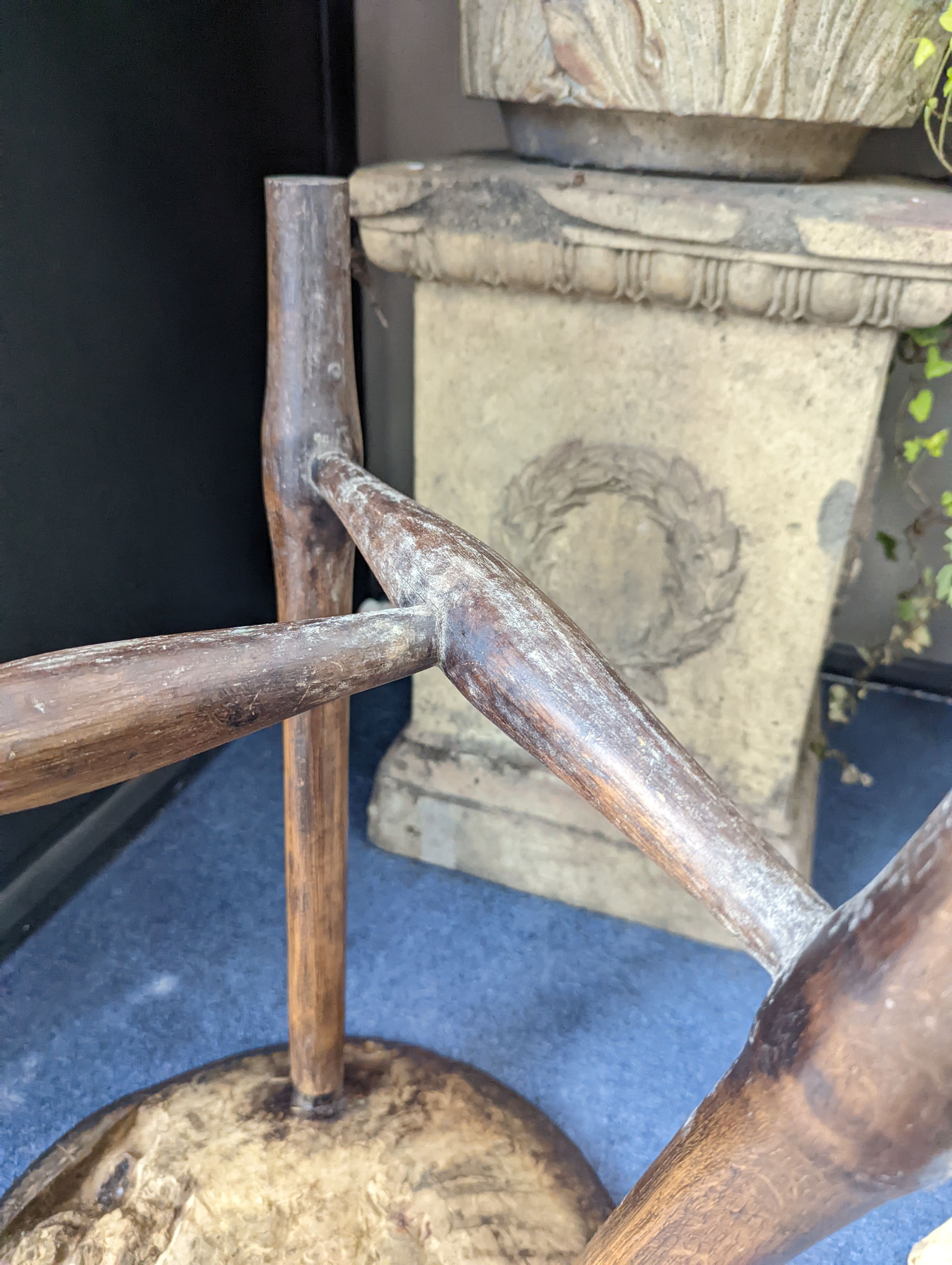 A circular burr elm and ash primitive cricket table with T shaped stretcher, diameter 44cm, height 61cm